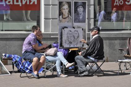 Арбатский уличный художник рисует шуточный шарж с натуры.