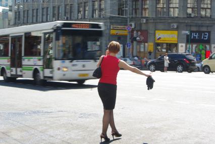 Молодая женщина голосует на улице, пытаясь остановить автобус, 29 иня 2010 года. Транспорт. Городской транспорт. Автобус. Девушка. Женщина. Голоусет на дороге. Город. Общественный транспорт.