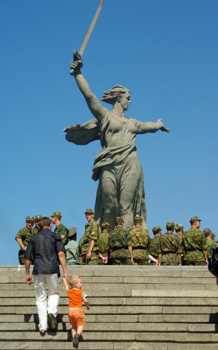 По ступеням Мамаева Кургана поднимаются солдаты и отец с маленьким сыном, 20 июня 2010 года. Мемориал. Волгоград. Праздник. День Победы. Родина Мать. Солдаты. Дети. Отец и сын. Детство.