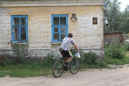 г. Осташков Россия Тверской области. 31 июля 2010 год. частный жилой дом, местный житель на велосипеде,  велосипедист, велосипед