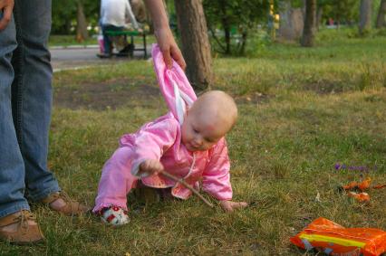 Падающего ребенка держит за капюшон мама,30 июня 2009 года. дети. Родители. Забота. Мама. Детство. Ушиб. Лето. Трава.