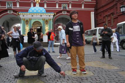 Туристы фотографируются на Красной площади, на отметке НУЛЕВОЙ КИЛОМЕТР, Москва,  23 августа 2010 года.  Бомжи. Заработок. Мелочь. Деньги. Сбор.