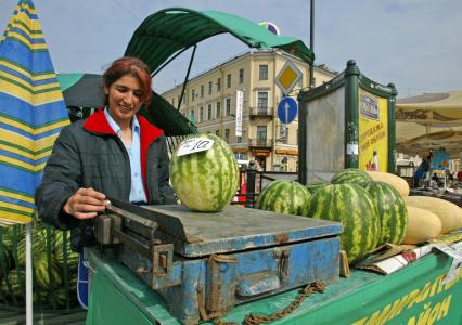 Уличная торговля арбузами. Продавец взвешивает арбуз на весах.