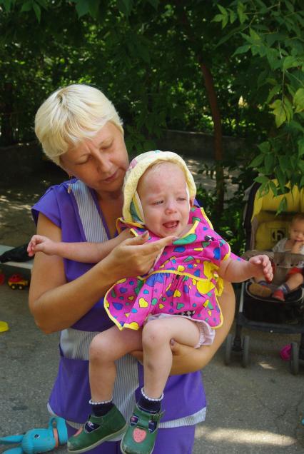 Сирота на руках воспитателя в детском доме, 2 августа 2010 года. Дети, детский дом, детдом, ребенок, манеж, игрушки, сиротка, воспитатель, учитель, мама, семтя, ребанок плачет, плач, слезы.