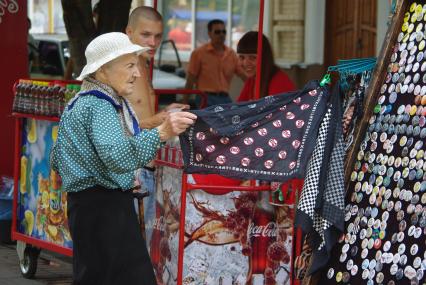 Бабка выбирает модный платок в уличной торговой палатке, молодые люди смеются смотря на старуху, 9 августа 2010 года, Бабка, старость, пенсия, мода, платок, значки, старики и молодежь, пенсионная реформа, стиль.