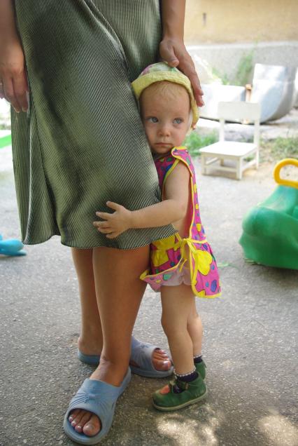 Сирота прижалась к ногам воспитателя в детском доме, 2 августа 2010 года. Дети, детский дом, детдом, ребенок, манеж, игрушки, сиротка, воспитатель, учитель, мама, семтя, ребанок плачет, плач, слезы, родители и дети.