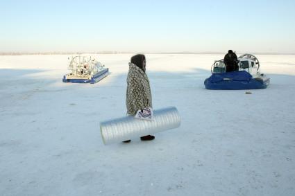 22.01.2010 Самара, Россия. Женщина зимой на берегу Волги идет на переправу на судно на воздушной подушке.