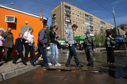 01.09.2010 Самара, Россия. Милиционер помогает прохожим преодолеть водный поток, образовавшийся в результате прорыва водопровода.