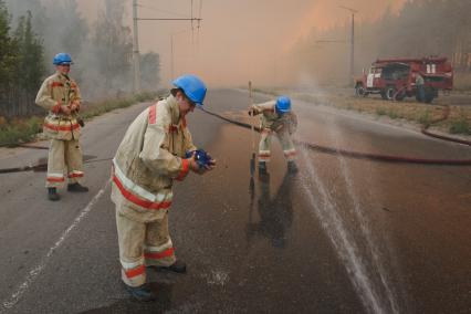 03.09.2010 Тольятти, Россия. Пожарные МЧС мочат водой одежду, чтобы спастись от перегрева на тушении лесного пожара.