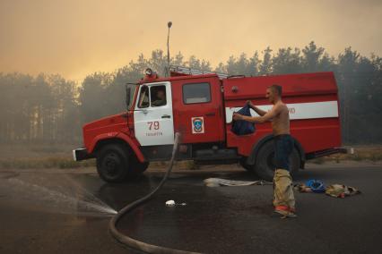 03.09.2010 Тольятти, Россия. Пожарный мочит водой одежду, чтобы спастись от перегрева на тушении лесного пожара.