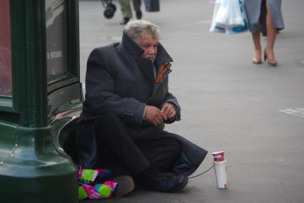 Мужчина в шинеле с георгиевской ленточкой в петличке просит милостыню на улице, Тверская улица, Москва, 7 сентября 2010 года. Милостыня, бомж, попрошайка, 9 мая, шинель, седина, старость, бедность, деньги, нищета, нищий