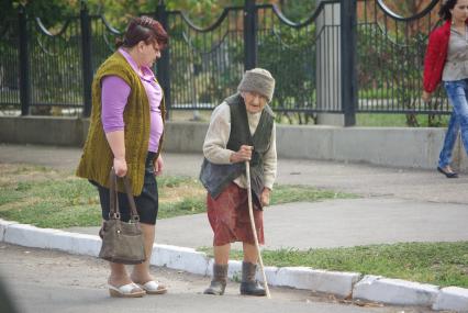 Бабулька с палочкой из ветки дерева, в галошахи фуфайке на улице города, 28 сентября, Саратов. Старость, пенсия, пенсионная реформа, радикулит, возраст, бабушка, бабка, пенсионер, социальынй работник, помощь.