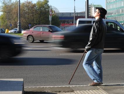 Слепой мужчина стоит у дороги