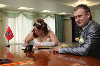 Дата: 26.06.2010, Время: 11:32. Молодая пара подтверждает свои отношения росписью. На снимке: невеста ставит свой автограф.