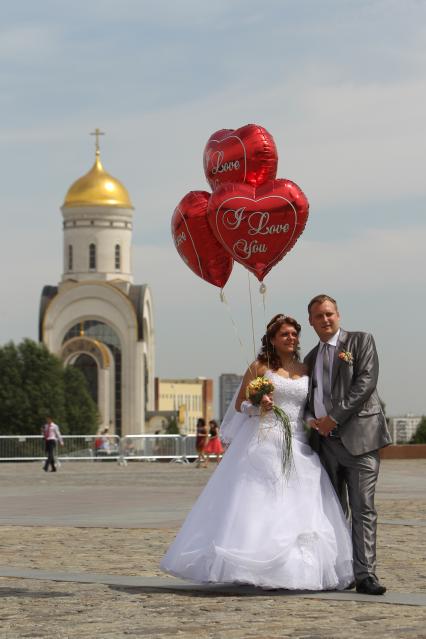 Дата: 26.06.2010, Время: 13:49. Молодая пара позирует / стоит на фоне Церкви Георгия Победоносца на Поклонной горе.