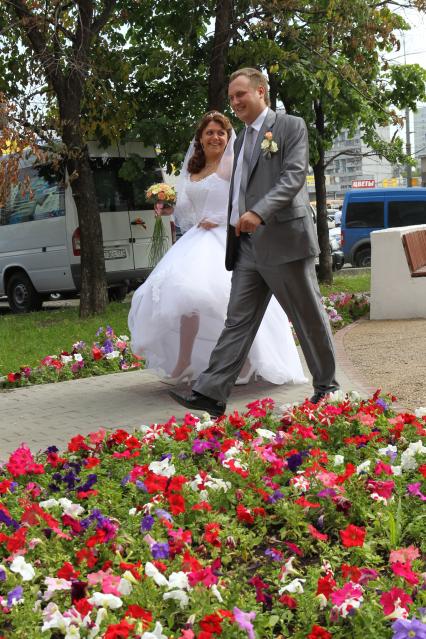 Дата: 26.06.2010, Время: 10:49. Молодая пара прогуливается по городу Москве. На снимке: идут мимо клумбы с цветами.