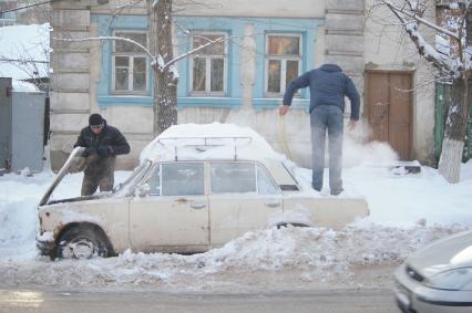 Занесенную снегом машину едетоткапывают из сугроба владельцы, Саратов, 21 декабря 2009 года. Автомобиль, авто, снег, сугроб, город, дорога, зима, холода, мороз