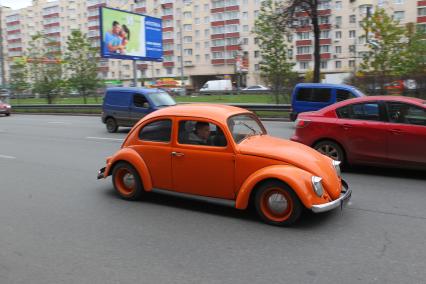 Оранжевый Volkswagen beatle едет в автомобильном потоке. 10 ноября 2010 года.