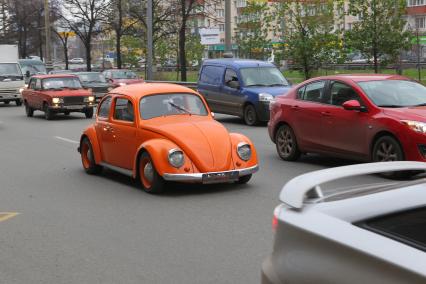 Оранжевый Volkswagen Beatle едет в потоке машин. 10 ноября 2010 года.