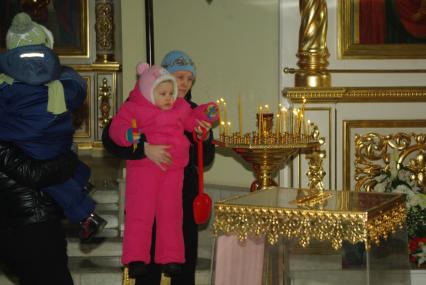 Мама с ребенком в церкви ставит свечку, Саратов, 3 февраля 2010 года. Церковь, вера, христианство, дети, свечки, пост, праздник, Рождество, служба, религия.