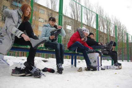 Дети одевают коньки сидя на лавочке перед школой, 22 декабря 2010 года, Саратов. школьники, дети, каток, коньки, зима, зимние забавы, каникулы, развлечения, отдых, мальчики и девочки, школа, перемена, урок физкультуры, закалка.
