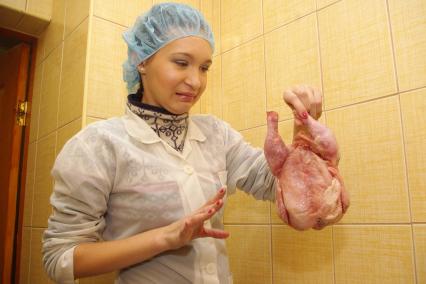 Девушка в белом халате и чепчике брезгливо смотрит на замороженную курицу, Саратов, 23 декабря 2010 года. Курица, полуфабрикат, проверка качества, сертификация, некачественный товар, заморозка, окорочка, мясная промышленность, антисанитария, санэпиднадзор, испорценный продукт, молодая хозяйка, повар, общепит,