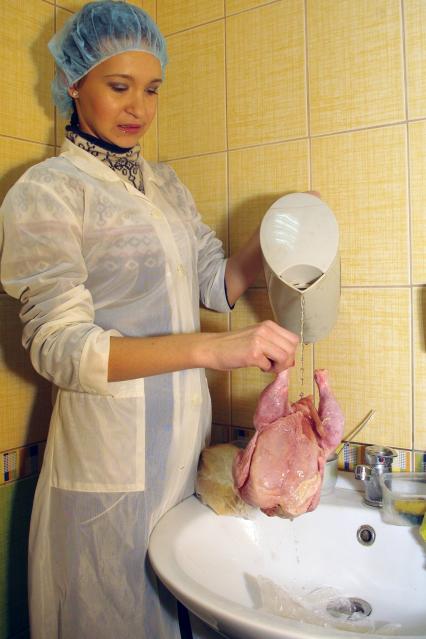Девушка в белом халате и чепчике моет в раковине замороженную курицу, Саратов, 23 декабря 2010 года. Курица, полуфабрикат, проверка качества, сертификация, некачественный товар, заморозка, окорочка, мясная промышленность, антисанитария, санэпиднадзор, испорценный продукт, молодая хозяйка, повар, общепит,