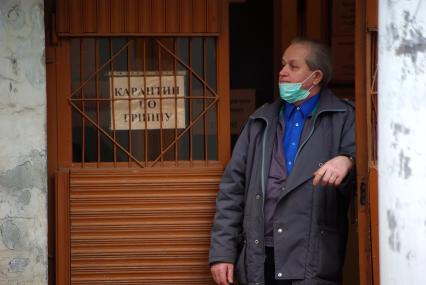 Мужчина в маске стоит у входа в здание, на котором висит табличка \"Карантин по гриппу\", Саратов, 4 декабря 2009 года. Карантин, грипп, свиной грипп, маска, эпидемия, болезнь.