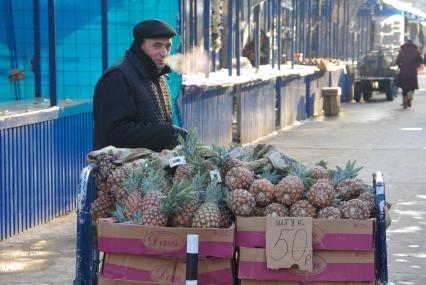 Мужчина неславянской внешности продает на рынке ананасы, на табличке надпись \"Штук- 50 рублей\", Саратов, 20 января 2011 года. Зима, рынок, продажа, ананас, гастарбайтер, нелегал, нелегальная торговля, уличная торговля, отсутствие сертификатов, качество, сертификация.
