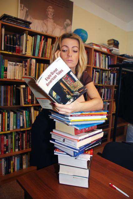 Студентка в библиотеке читает книгу, облокотившись на стопку учебников, Саратов, 1 февраля 2011 года. Сессия, подготовка к экзаменам, английский язык, изучение иностранного языка, иностранный язык, книги, учебники, библиотека, читальный зал, девушка, блондинка и книжки, экзамен, занятия, университет, ВУЗ, знания.