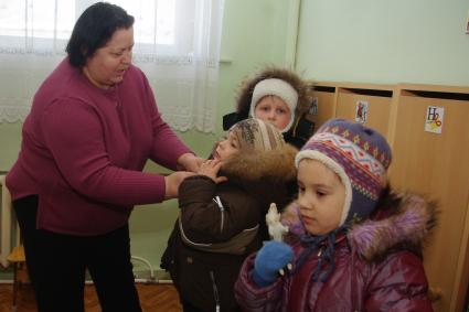 Дети в раздевалке детского сада переодеваются- собираются на прогулку, Саратов, 3 февраля 2011 года. Дети, детсад, детский сад, прогулка, одежда, зима, группа, воспитатель