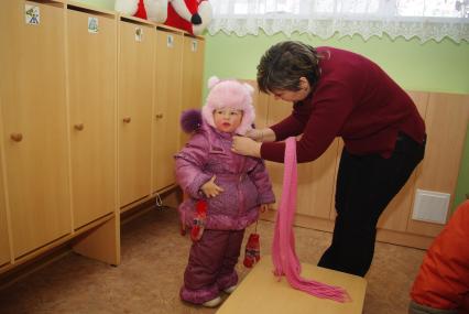 Дети в раздевалке детского сада переодеваютсяпосел прогулки на свежем воздухе, Саратов, 3 февраля 2011 года. Дети, детсад, детский сад, прогулка, одежда, зима, группа, воспитатель.