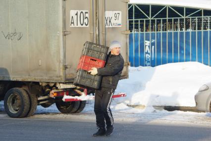 Грузчик несет контейнеры с хлебом. Доставка продовольствия. Хлеб. Продукты. Продовольствие. Зима. Мороз. 17 февраля 2011 года.