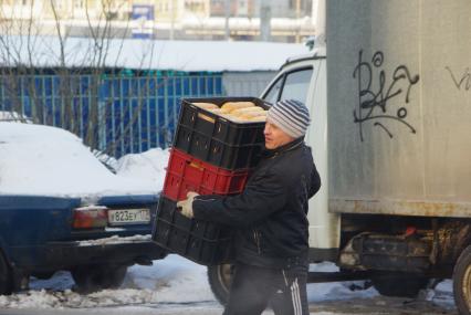 Грузчик несет контейнеры с хлебом. Доставка продовольствия. Хлеб. Продукты. Продовольствие. Зима. Мороз. 17 февраля 2011 года.