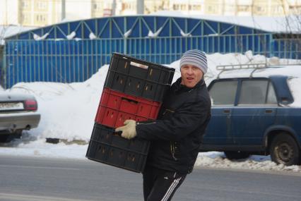 Грузчик несет контейнеры с хлебом. Доставка продовольствия. Хлеб. Продукты. Продовольствие. Зима. Мороз. 17 февраля 2011 года.