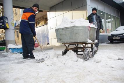 Гастарбайтеры убирают снег в корыто на тележке, Москва, 17 февраля 2011 года.
