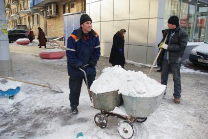 Гастарбайтеры убирают снег в корыто на тележке, Москва, 17 февраля 2011 года.