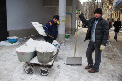 Гастарбайтеры убирают снег в корыто на тележке, Москва, 17 февраля 2011 года.