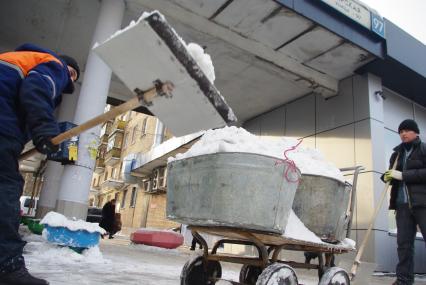 Гастарбайтеры убирают снег в корыто на тележке, Москва, 17 февраля 2011 года.