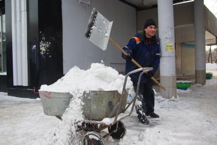 Гастарбайтеры убирают снег в корыто на тележке, Москва, 17 февраля 2011 года.