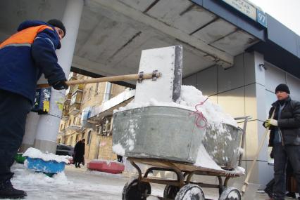 Гастарбайтеры убирают снег в корыто на тележке, Москва, 17 февраля 2011 года.