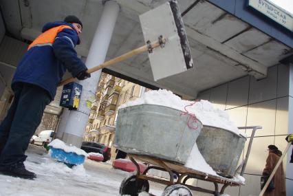 Гастарбайтеры убирают снег в корыто на тележке, Москва, 17 февраля 2011 года.