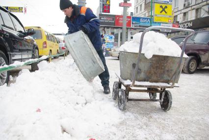 Гастарбайтеры убирают снег в корыто на тележке, Москва, 17 февраля 2011 года.