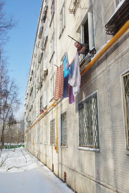Мужчина развешивает белье на окне дома -хрущевки, Москва, 17 февраля 2011 года. Хрущевка, старые дома, жилье под снос, хозяйственный мужчина, белье, идеальный муж, окно, квартира, жилье