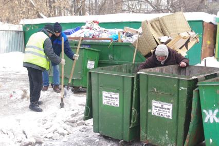 Пока гастарбайтеры в поте лица работают отбивая лед с асфальта, женщина самозабвенно роется в мусорке, Москва, 27 февраля 2011 года.