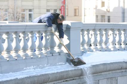 Мужчина лопатой сбрасывает снег из труднодоступного места, Москва, 10 марта 2011 года