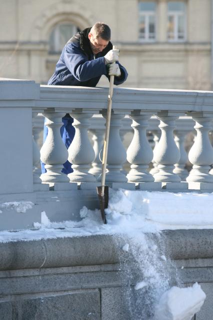 Мужчина лопатой сбрасывает снег из труднодоступного места, Москва, 10 марта 2011 года