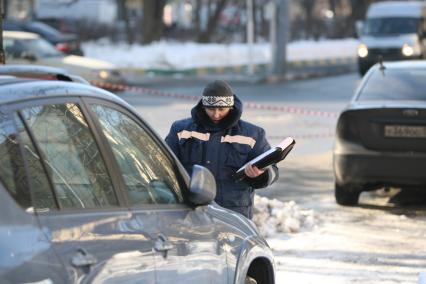 Эвакуатор поднимает автомобили, стоящие вдоль дороги, для очистки под ними снега, Москва, 2 марта 2011 года.