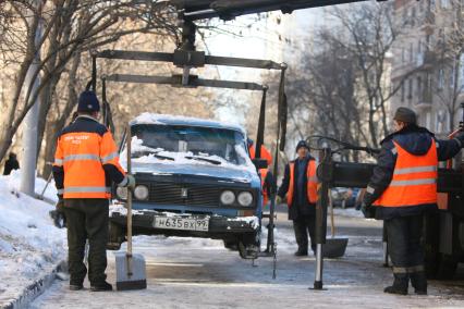 Эвакуатор поднимает автомобили, стоящие вдоль дороги, для очистки под ними снега, Москва, 2 марта 2011 года.