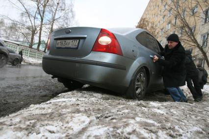 Автомобиль застрял в глубоком снегу. Люди, мужчина и женщина выталкивают машину. 3 марта 2011 года.